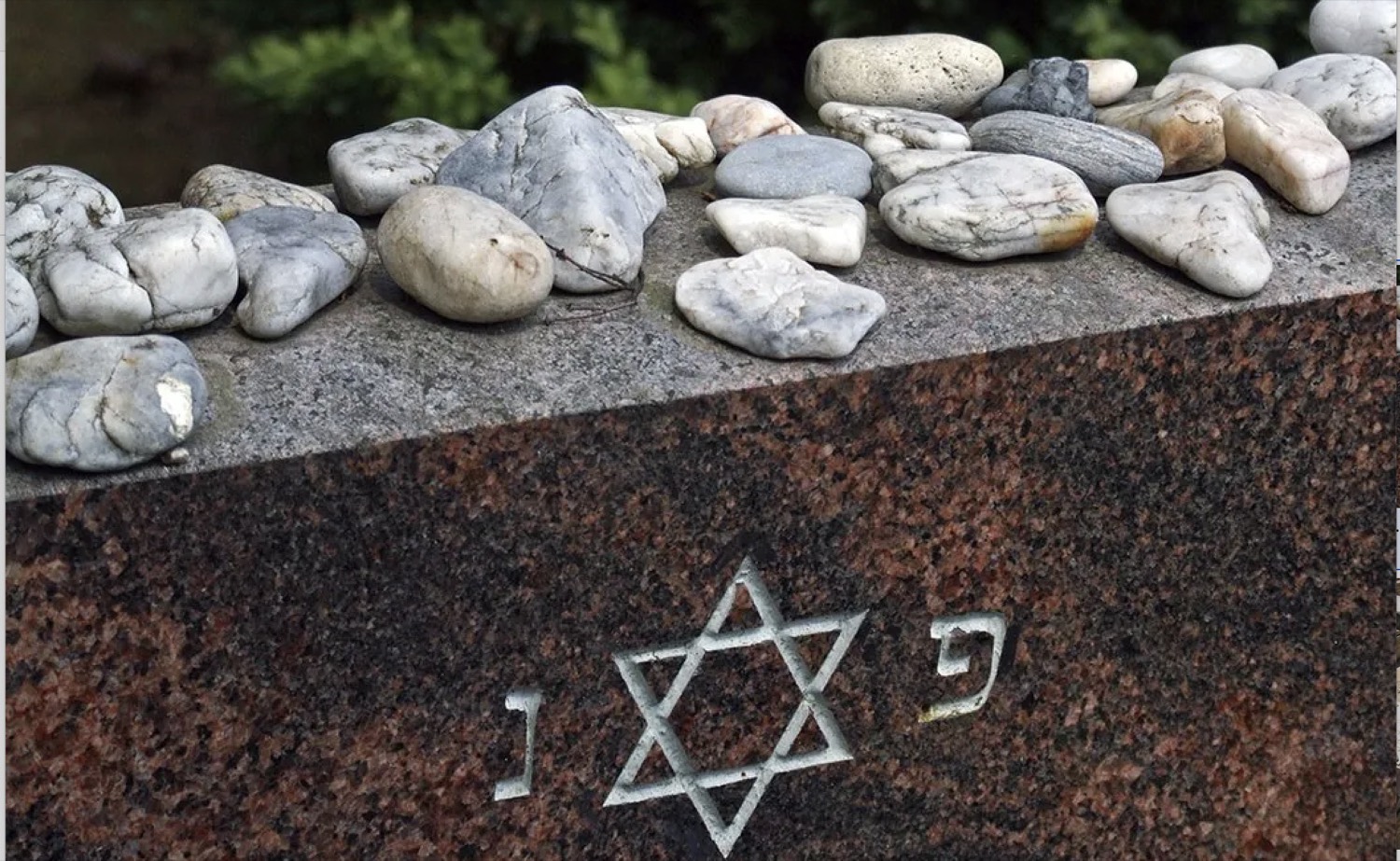 Visitor stones left on a Jewish granite headstone with a Star of David